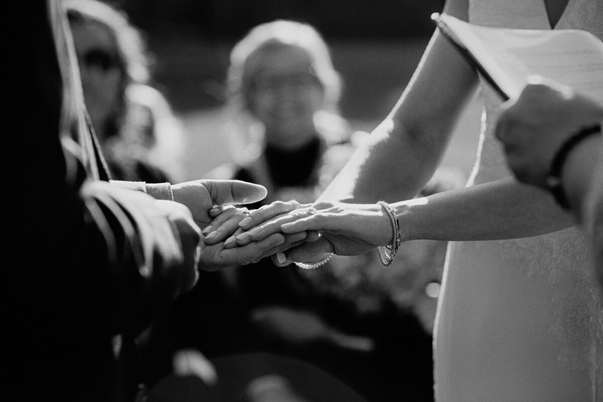 black-and-white-image-of-a-bride-and-groom-holding-hands-during-the-ceremony-1