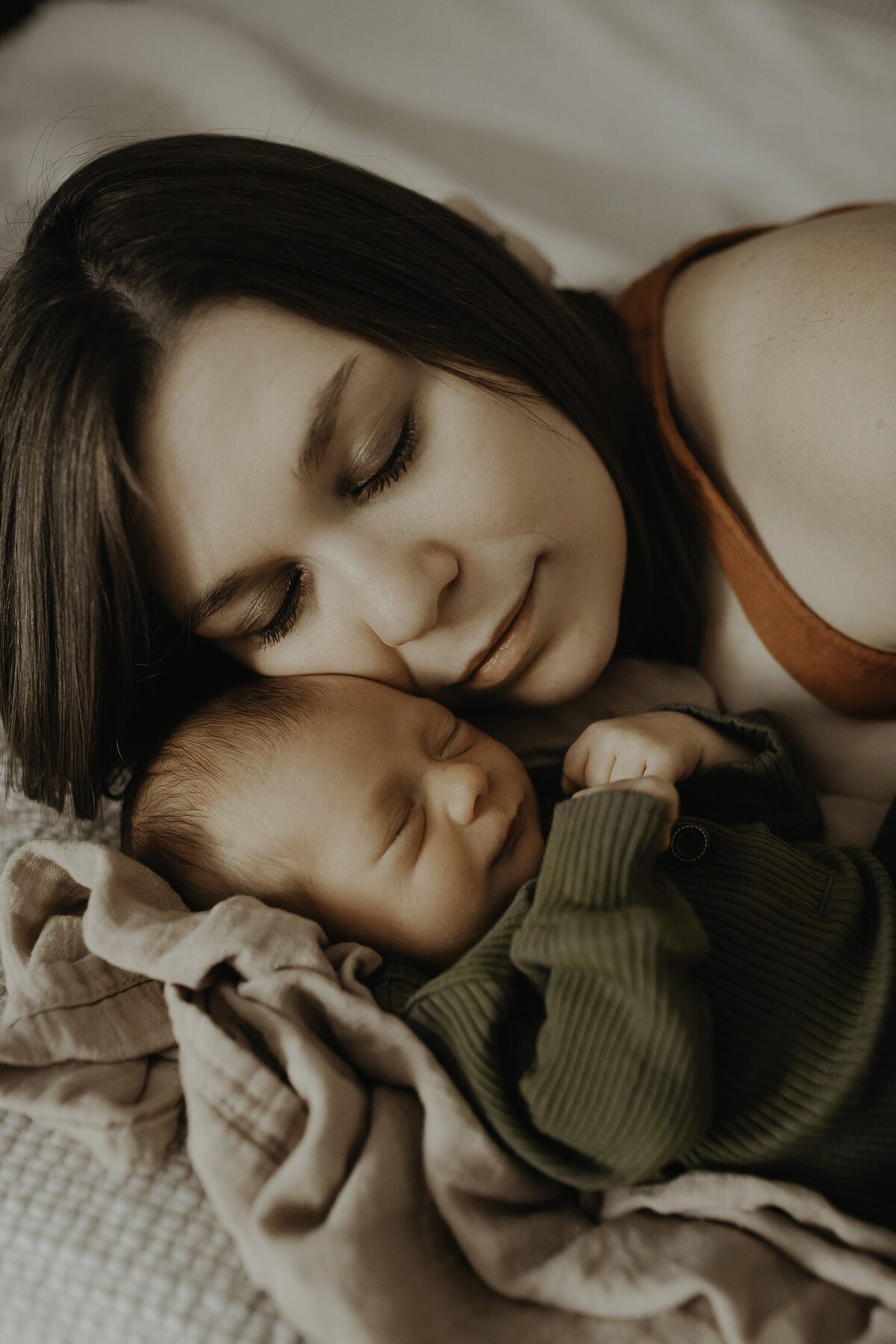 Verona B Photography captures an adorable sleeping newborn baby with his mom as she tenderly rests her check against his head. It is such an honor to capture these moments between a new baby and his momma in an in-home newborn session near Akron, Ohio.