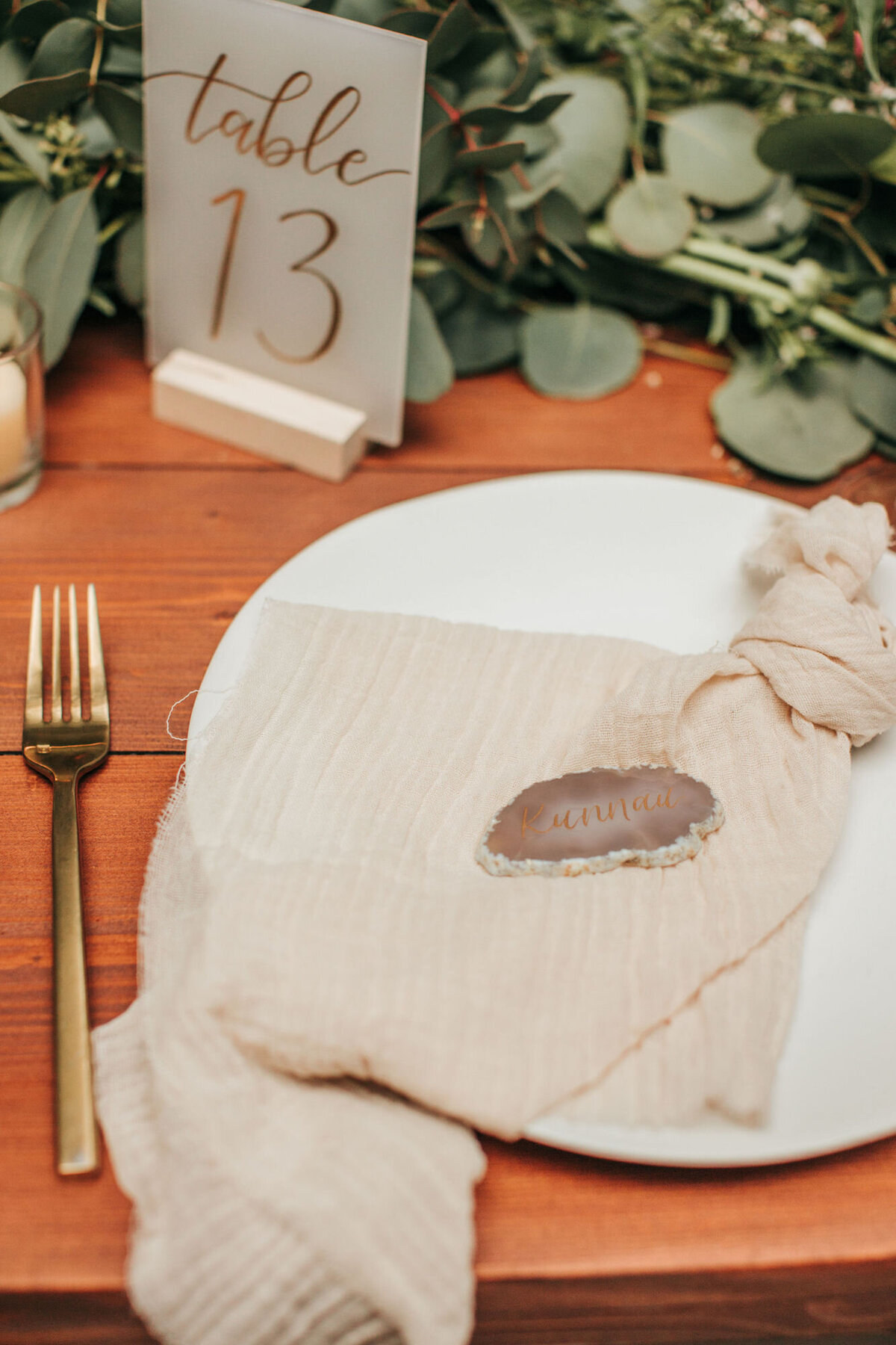 Neutral agate place card with gauze linens, next to a calligraphy table number