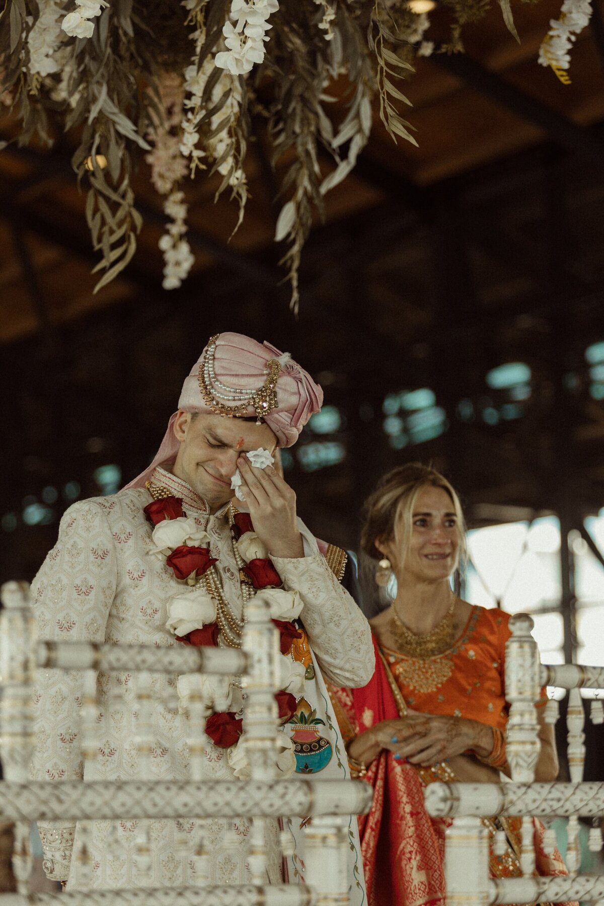A groom crying as he watches his fiance walk to him at their South Asian wedding ceremony.