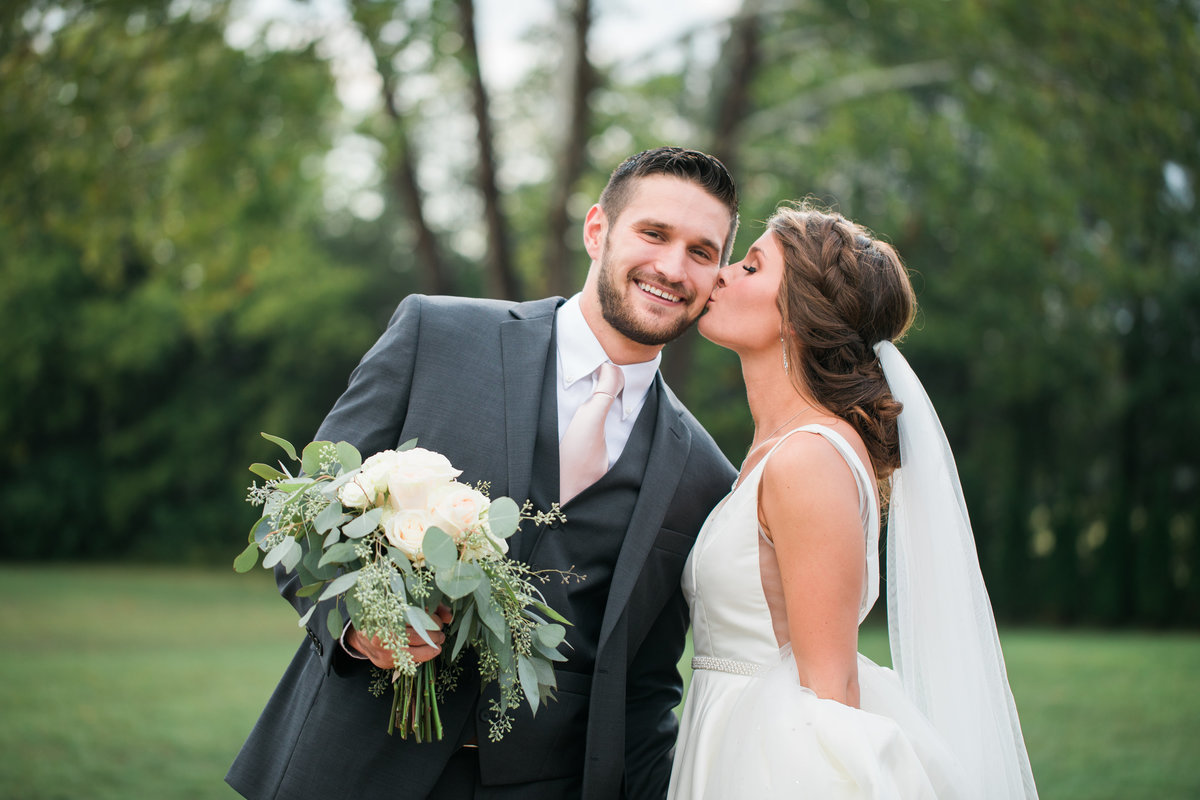 Bride kissing groom on the cheek.