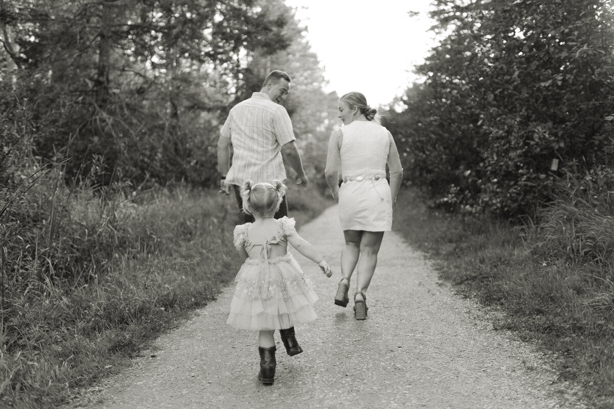 Toddler girl chases her parents down a dirt path during a Duluth, Minnesota family session.