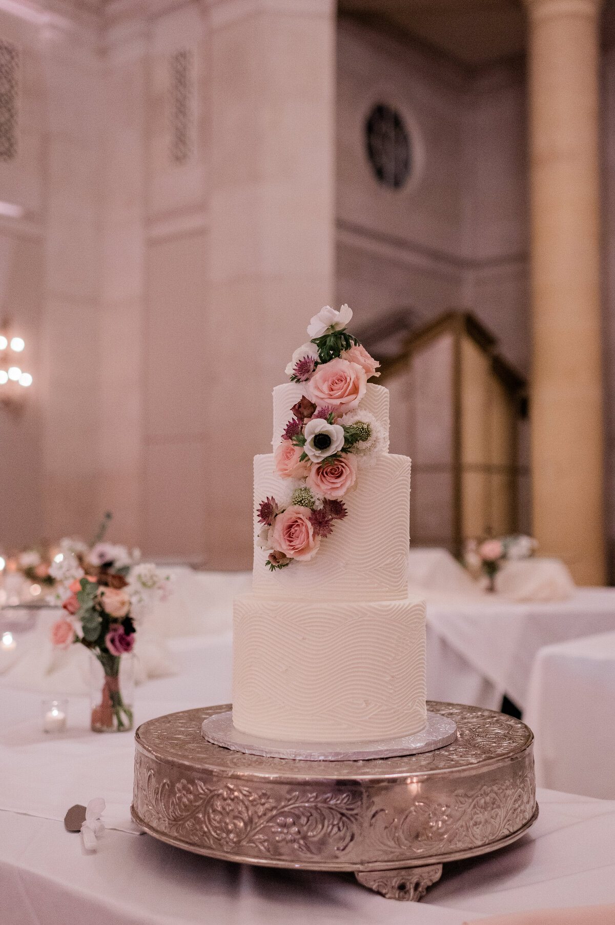 White wedding cake with pink and purple florals prior to being cut 