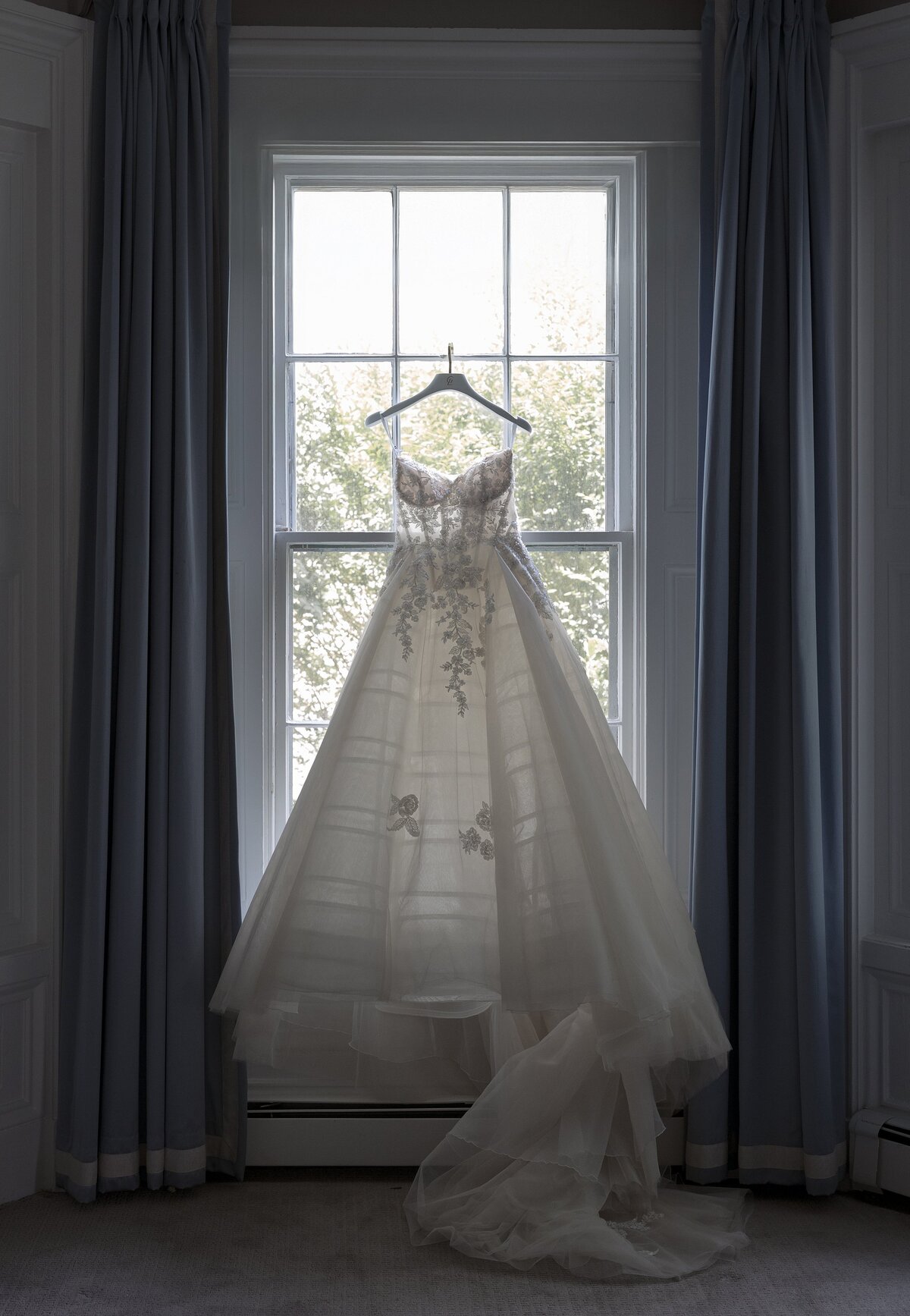 Wedding dress hangs in window during wedding in Newport.