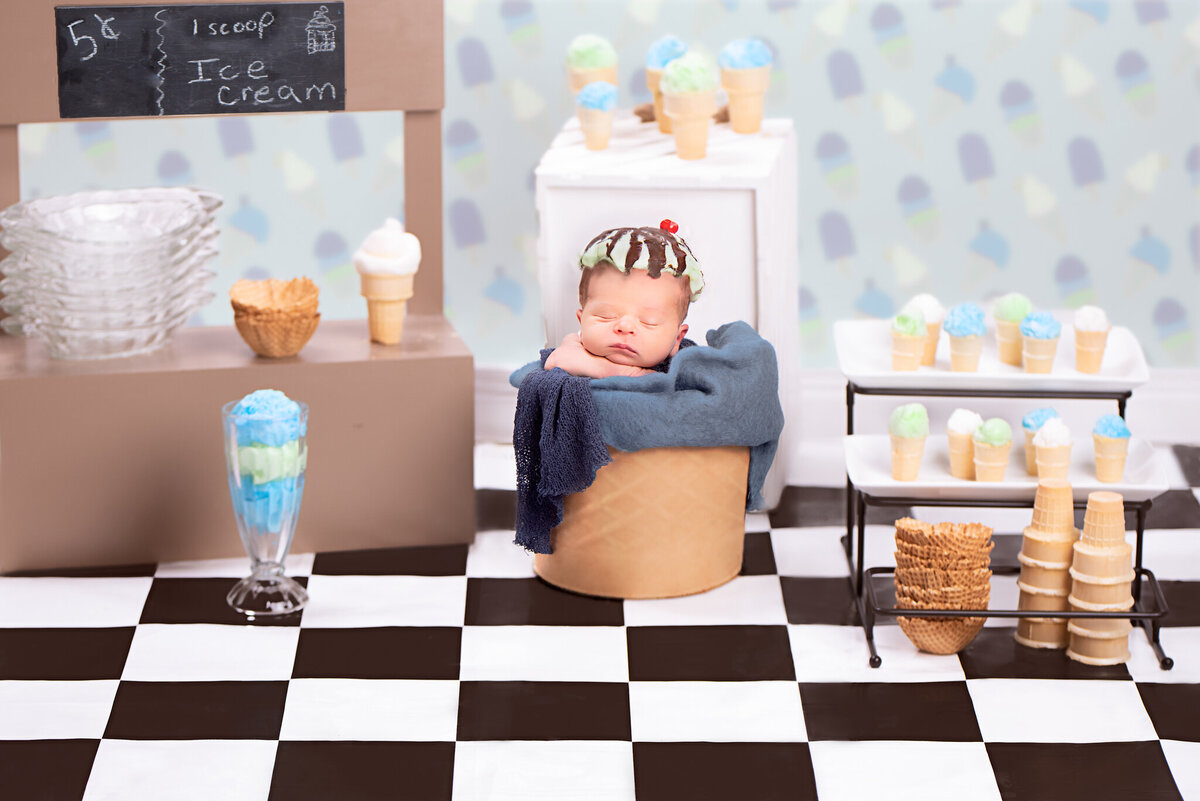 Newborn posed in an ice cream shop setup, featuring a chef's hat and baking props, captured in Overland Park, Kansas. A fun choice for families seeking creative and themed newborn photography in the Kansas City area