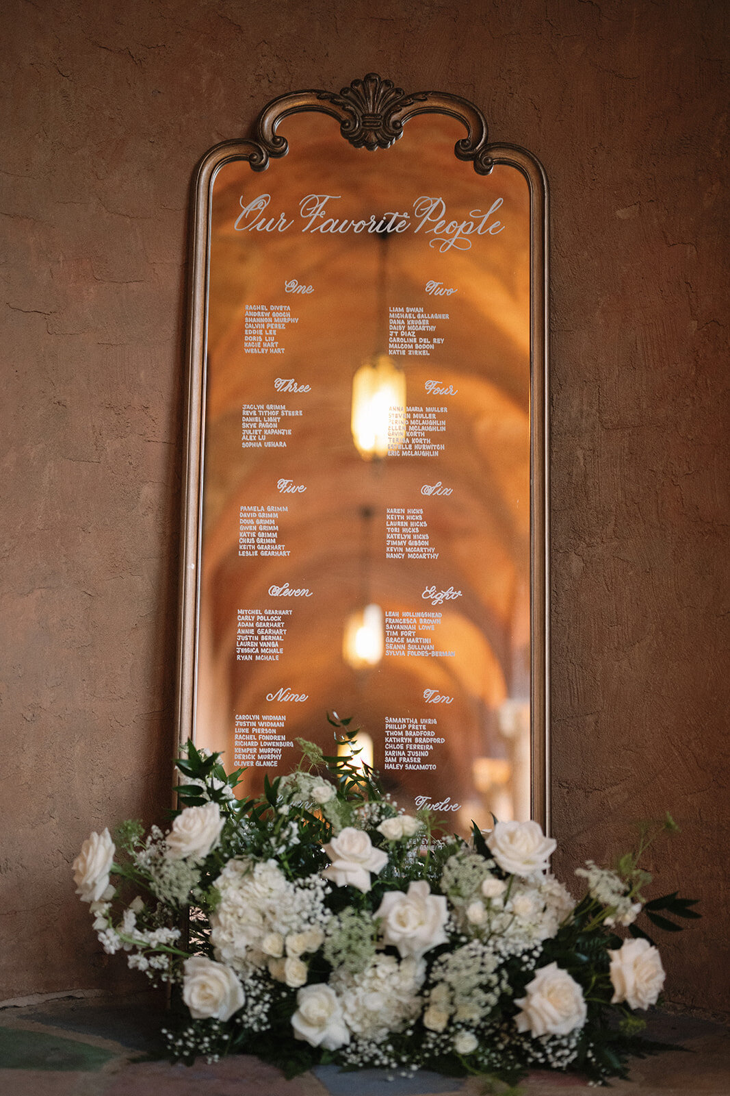Large gold wood mirror with ornate arches at the top and calligraphy for a seating chart