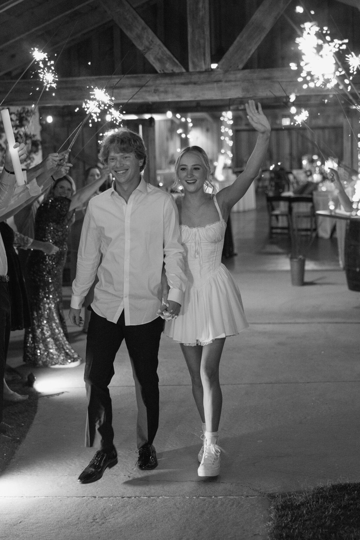 Bride and groom exit reception togetehr surrounded by guests