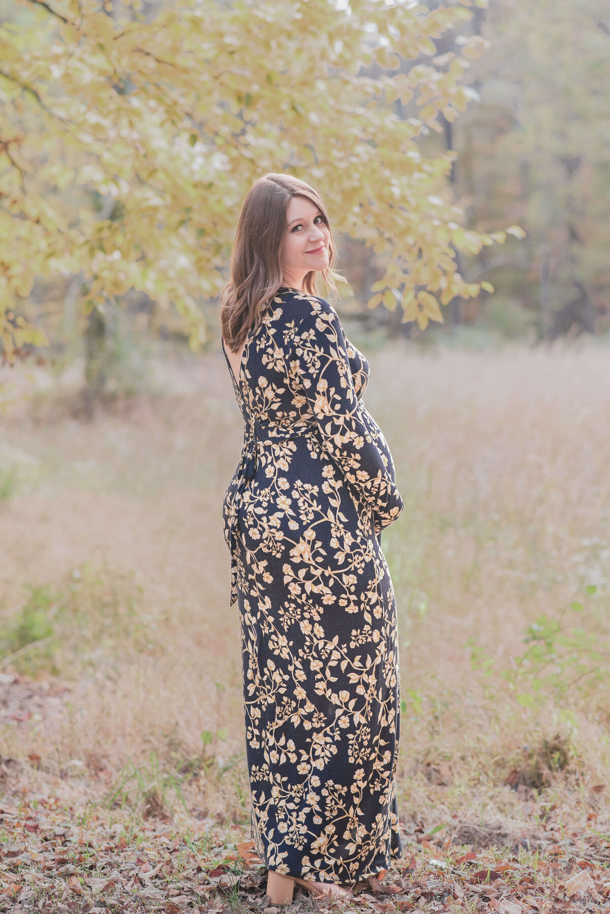 mom to be on a field with tall grass and fall leaves surround it
