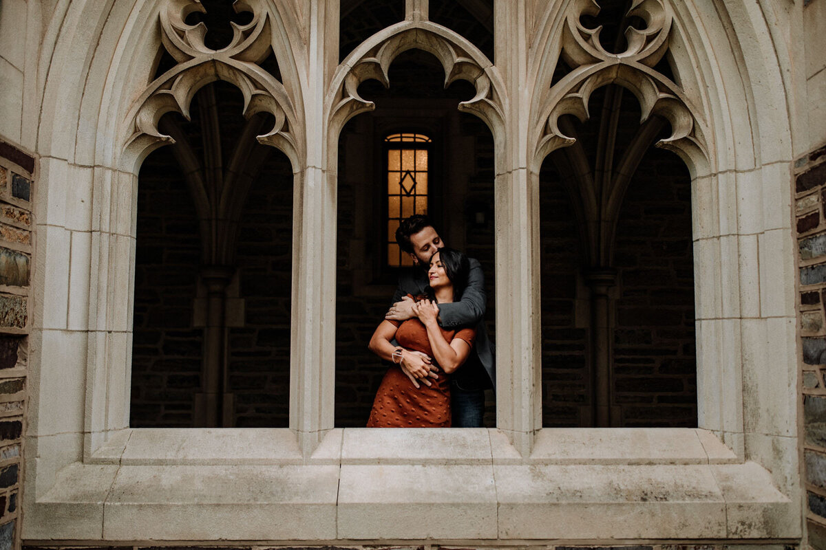 Bride and groom holding hands looking at each other while standing in front of rolling hills with the sunlight coming down on them