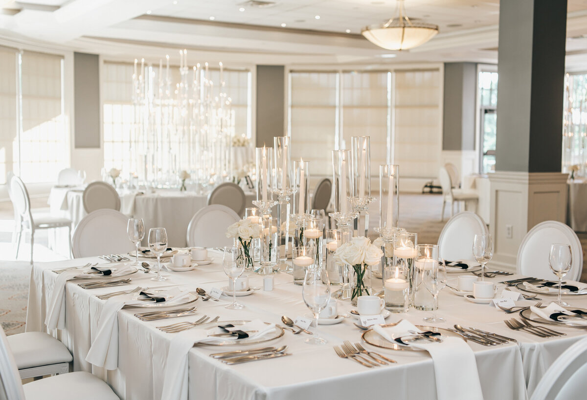 Elegant table settings with white accents and candles at a black tie wedding reception