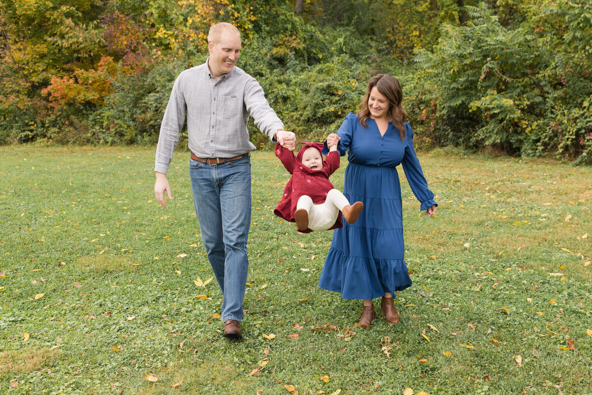 Mom and dad walking and swinging their baby girl