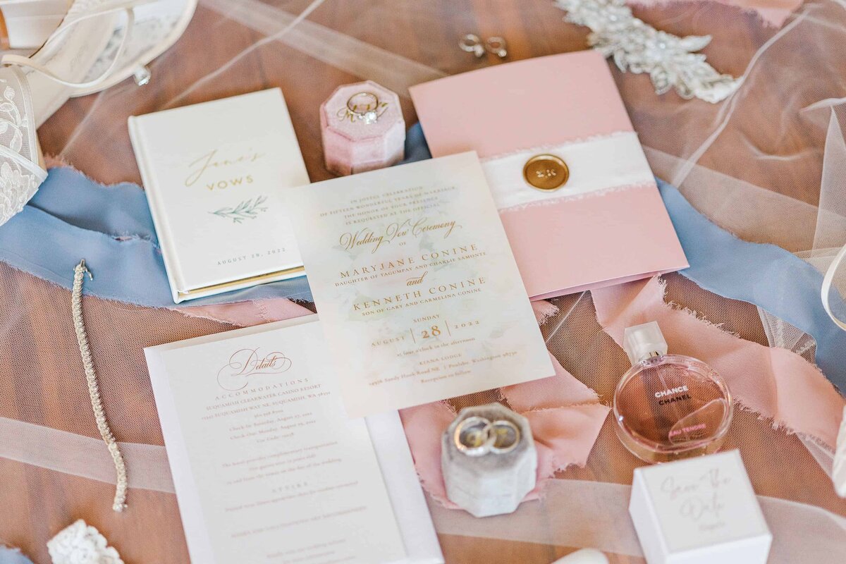 Flat lay photograph of various wedding details, including rings, invitations, save the dates, and important, heirloom jewelry