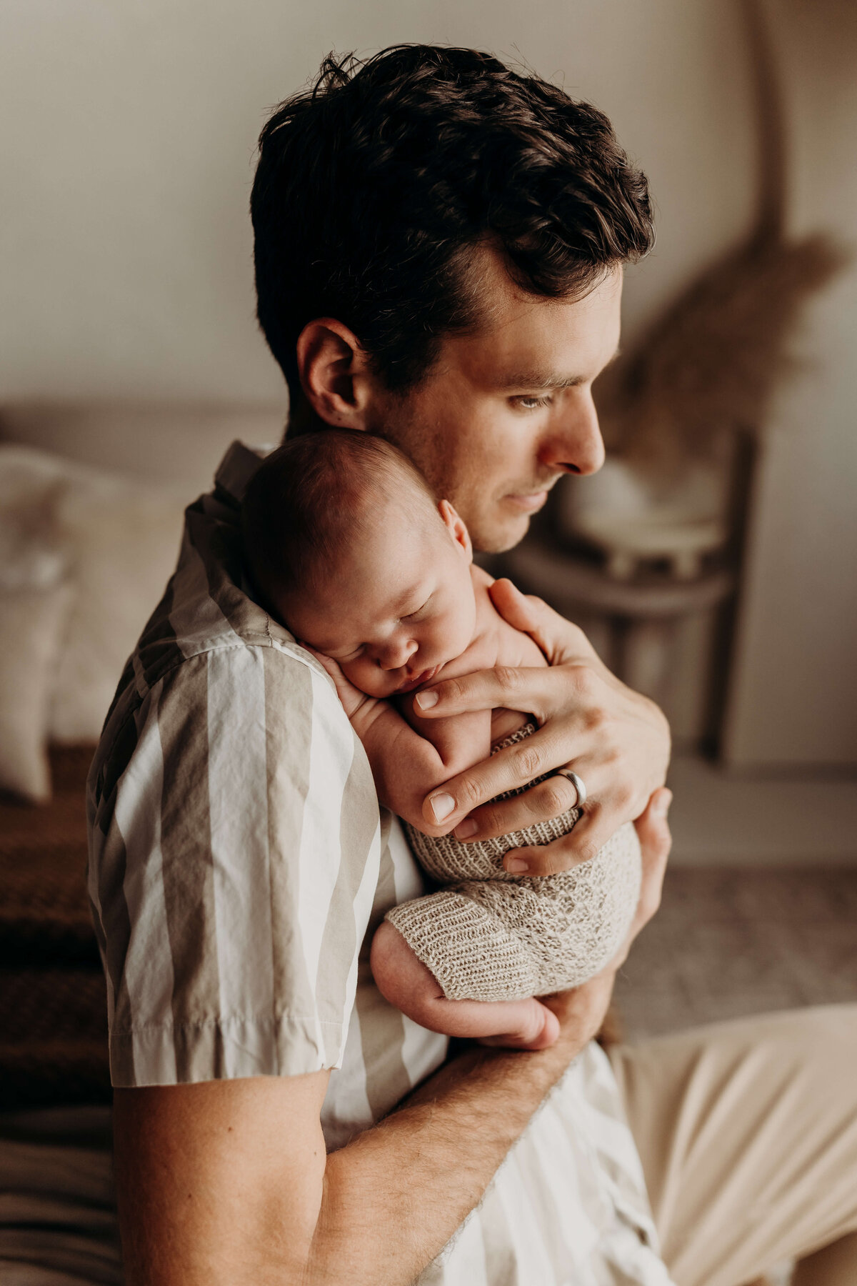 dad holds sleeping baby boy on his shoulder as he sleeps