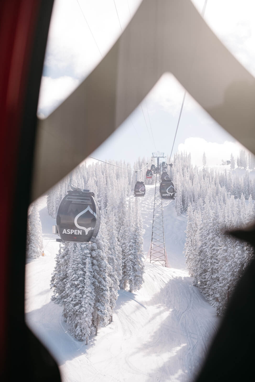 View from inside Aspen gondola showcasing light and snowy scene view of the mountain.