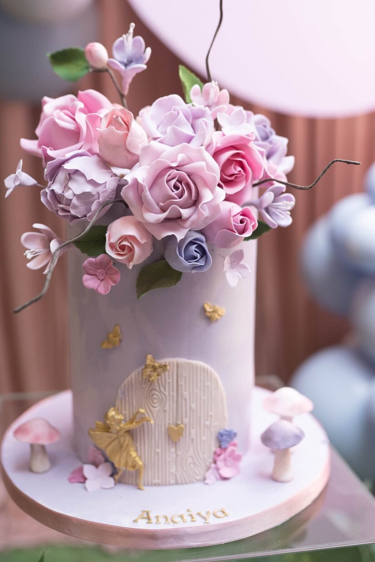 Small purple birthday cake with gold fairy and sugar flowers