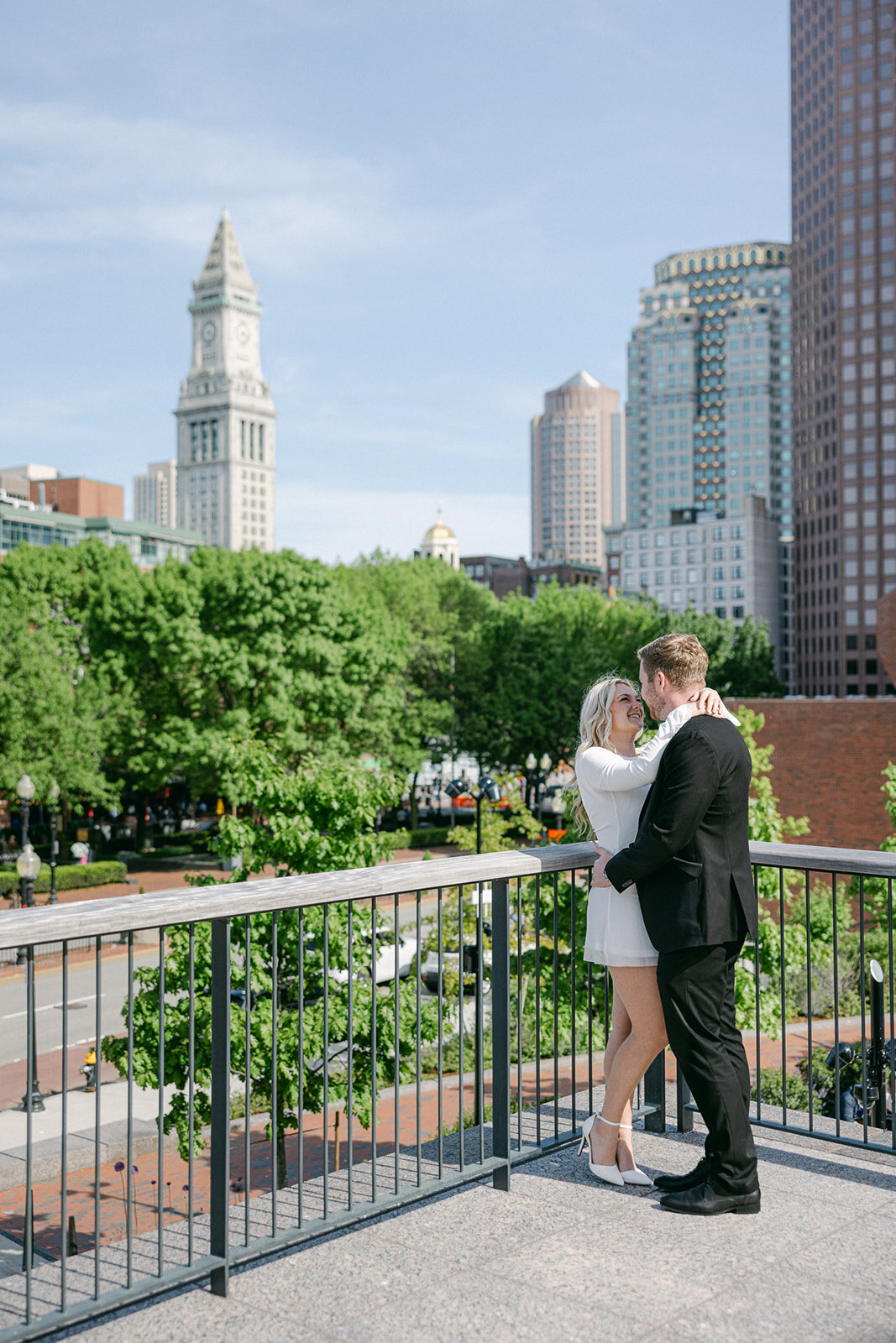 an engaged couple embracing with the city in the background