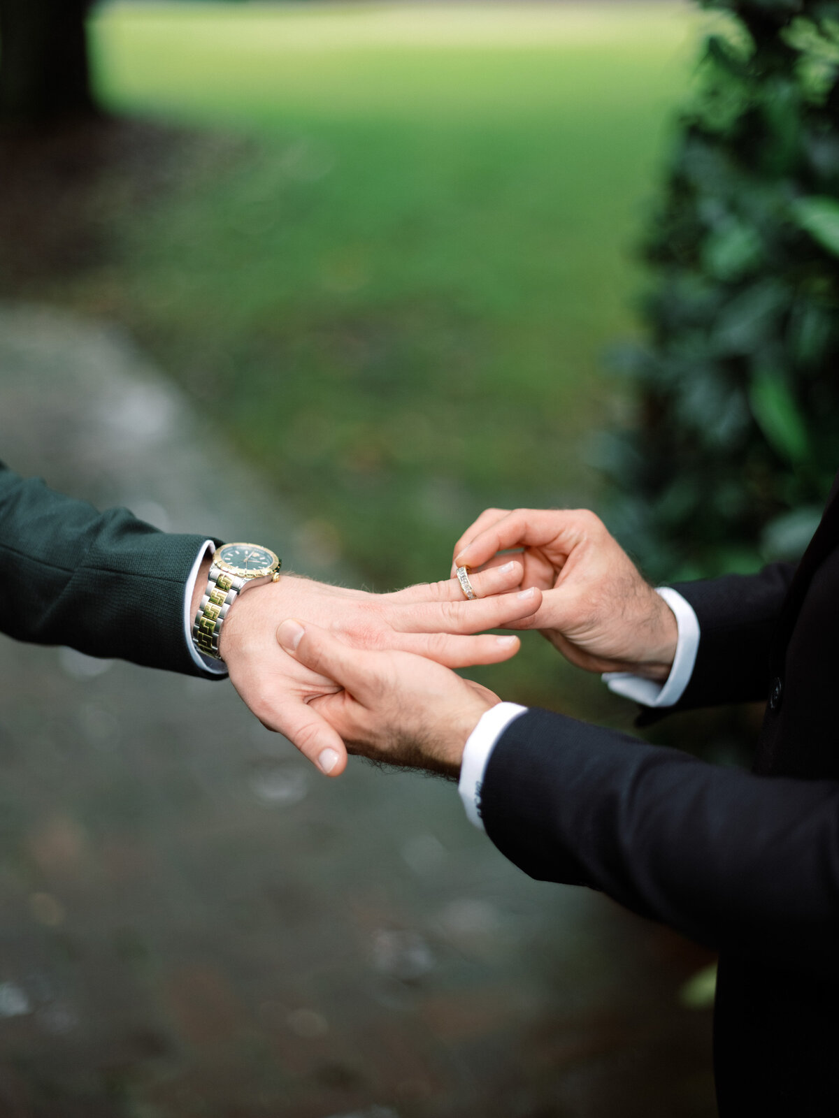 The touching moment of one groom placing a wedding ring on his partner's finger signifies their commitment, surrounded by an intimate and romantic Charleston.