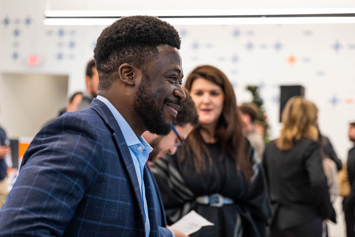 A person smiling as they mingle at a conference 