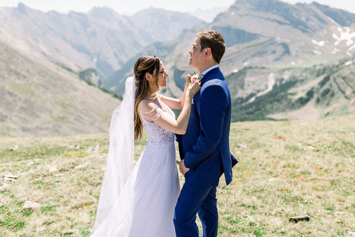 Bride-putting-on-a-flower-onto-the-groom-during-thier-mountain-elopement-wedding