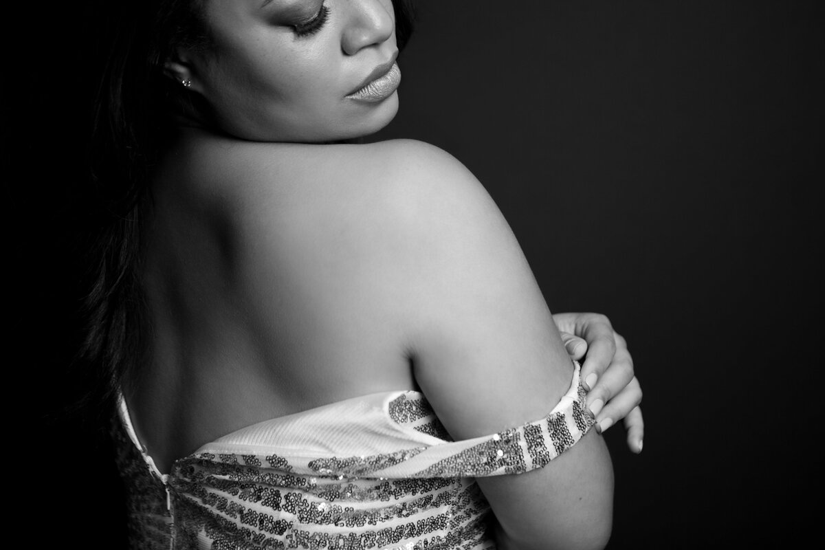Black and white photo taken in a New York photography studio by a boudoir photographer. Image of a woman with dress falling off the shoulder