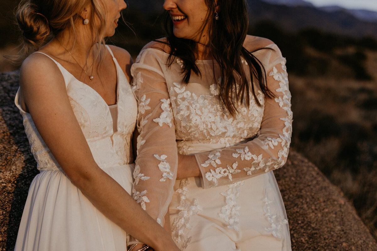 newlywed LGBTQ+ couple holding each other in front of the Sandia mountains in Albuquerque, New Mexico