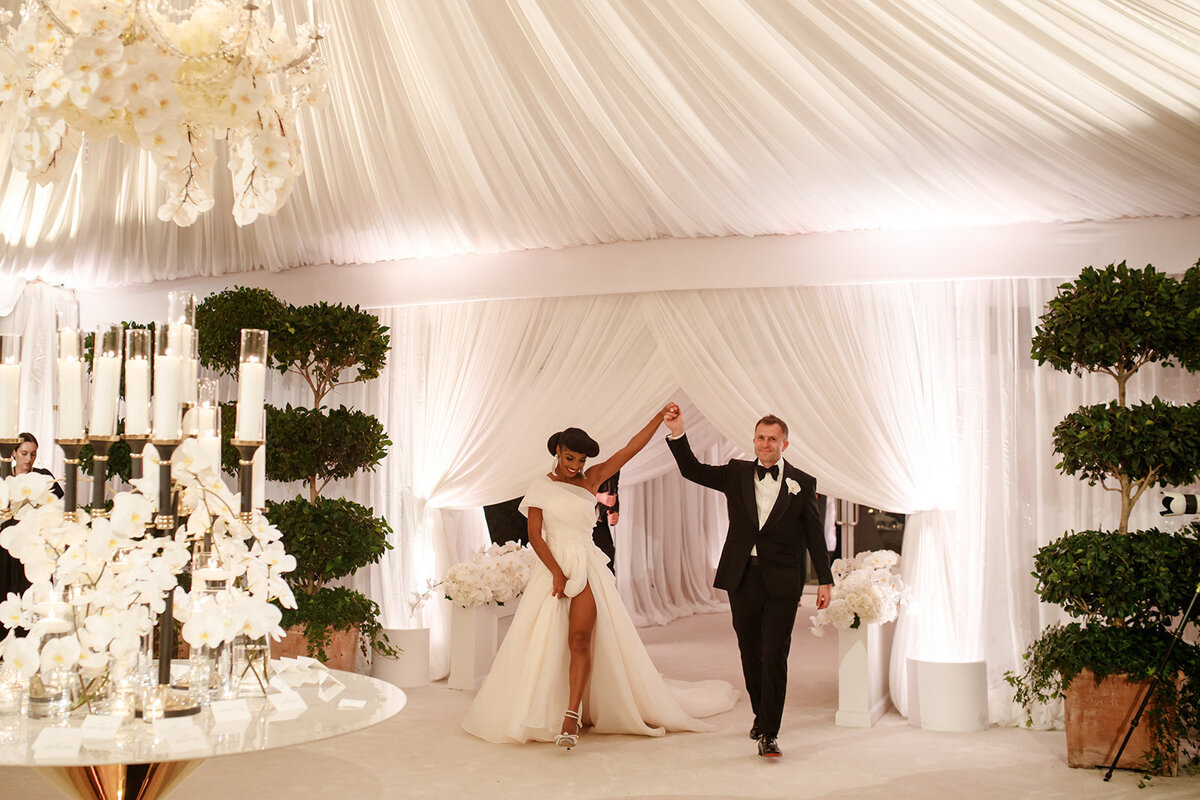 Bride and groom holding hands as the enter reception.