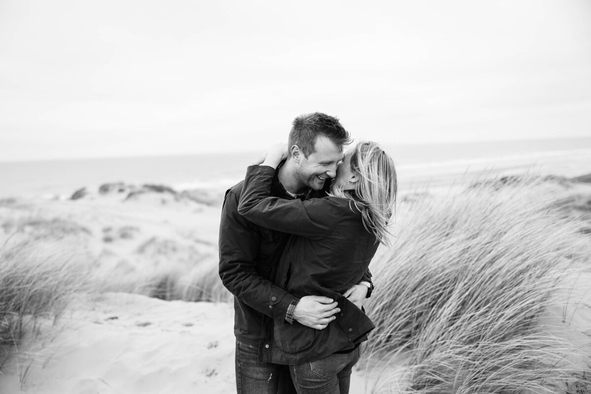 A couple on their engagement shoot hugging on top of a sand dune on Formby Beach