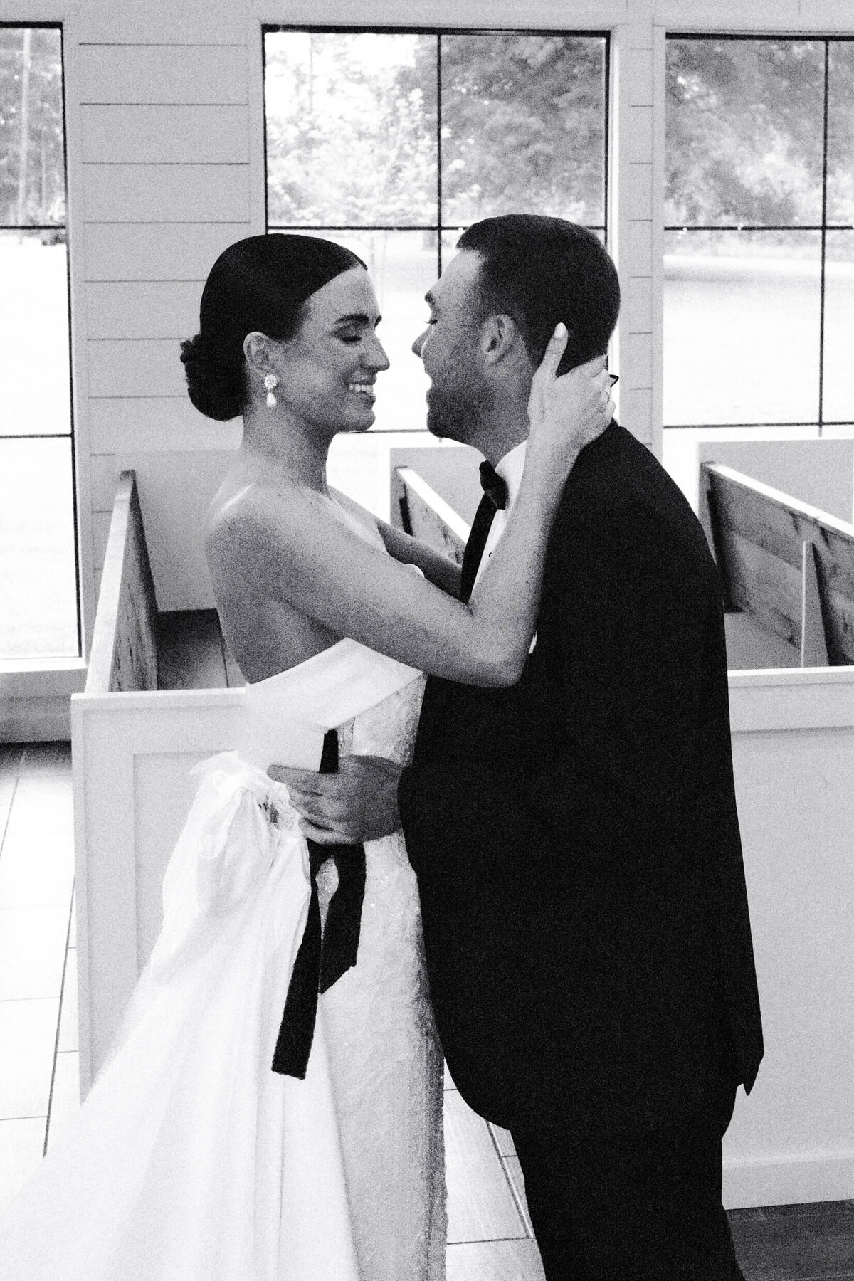 A candid black and white wedding day photo of the bride and groom during their first look
