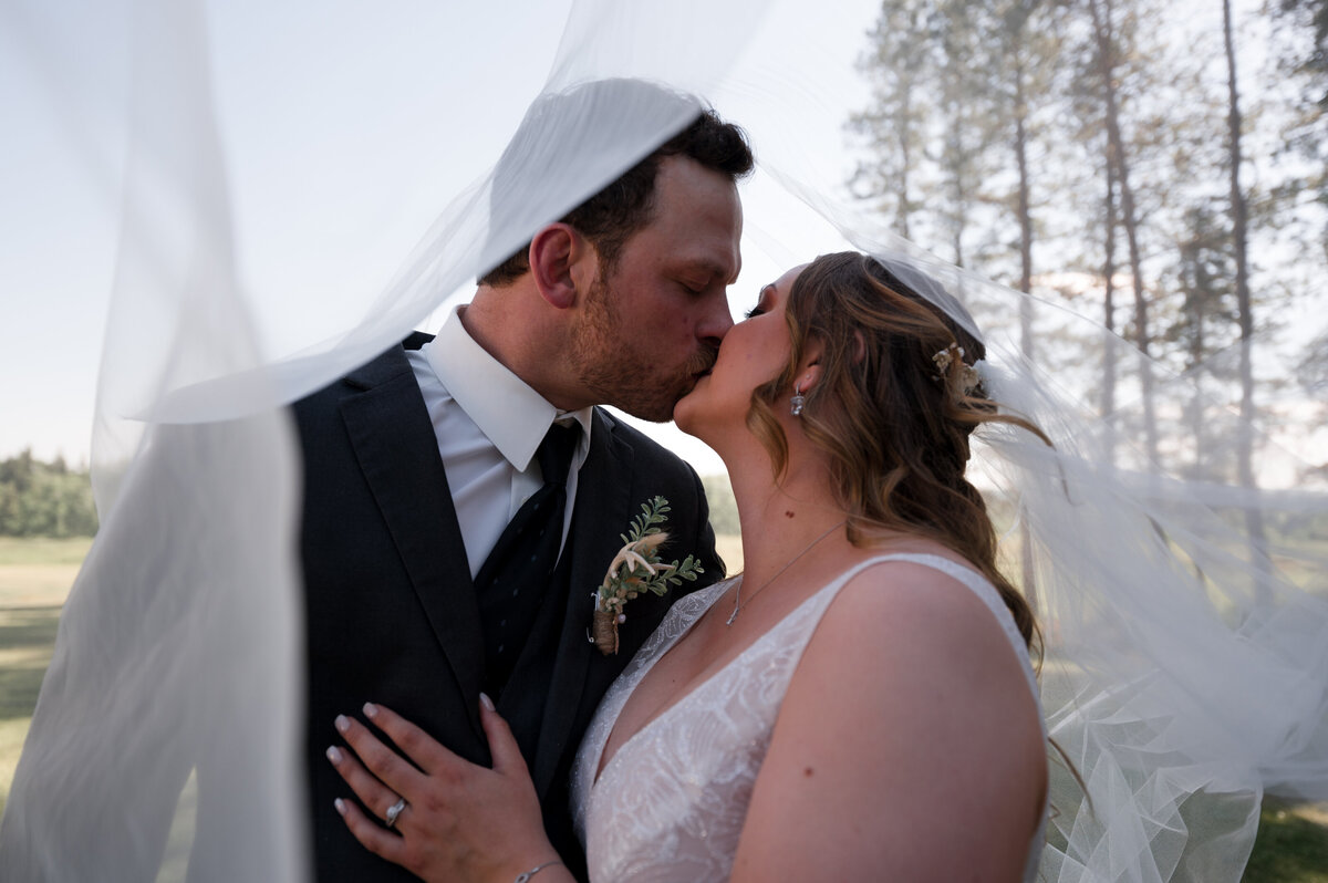 bride and groom kissing under veil