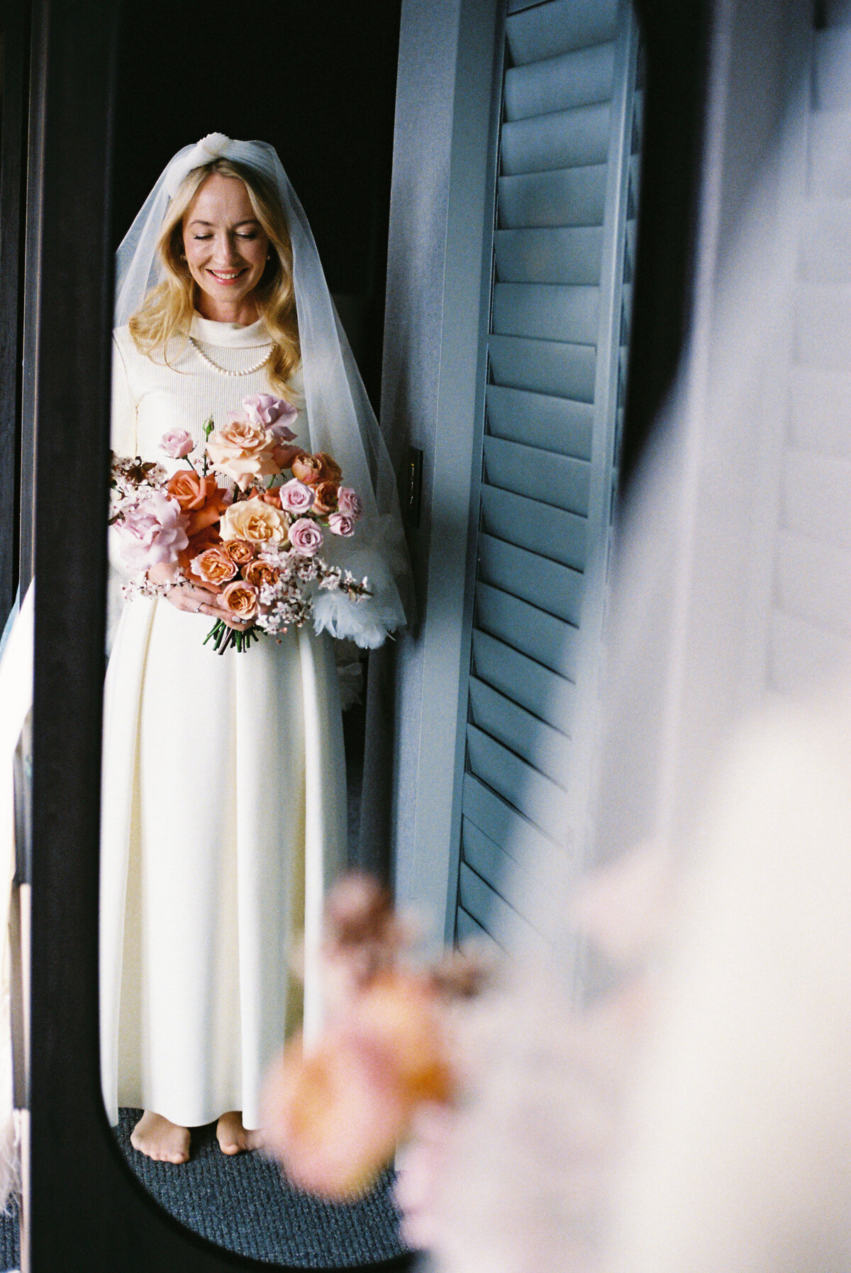 Classic bride holding bouquet looking in the mirror at her Major Domo accommodation in Queenstown