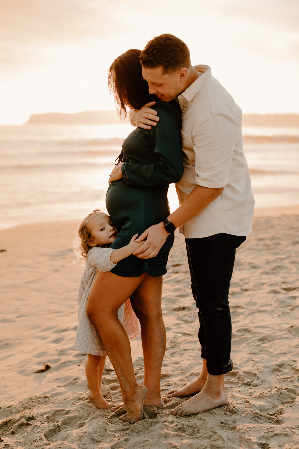 maternity photos of man, woman, and little girl at Coronado beach