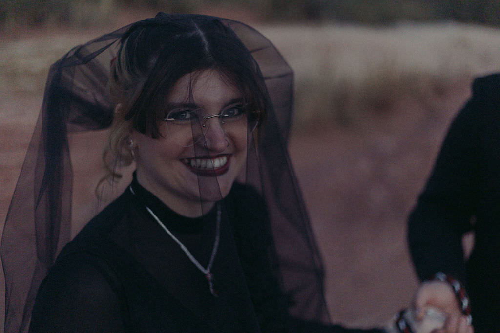 A person in a black veil smiling.