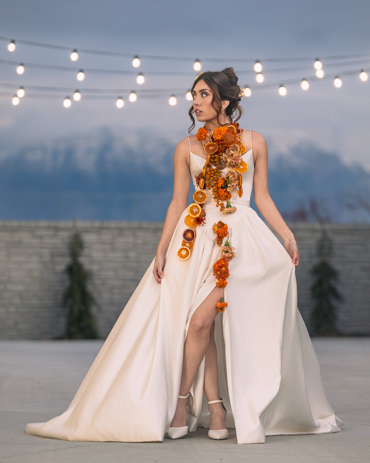 Salt Lake City wedding photographer capturing an editorial bride outdoors with mountains and string lights in the background. Moonlit Photo Utah bridal portraits featuring cinematic lighting and modern wedding styling.