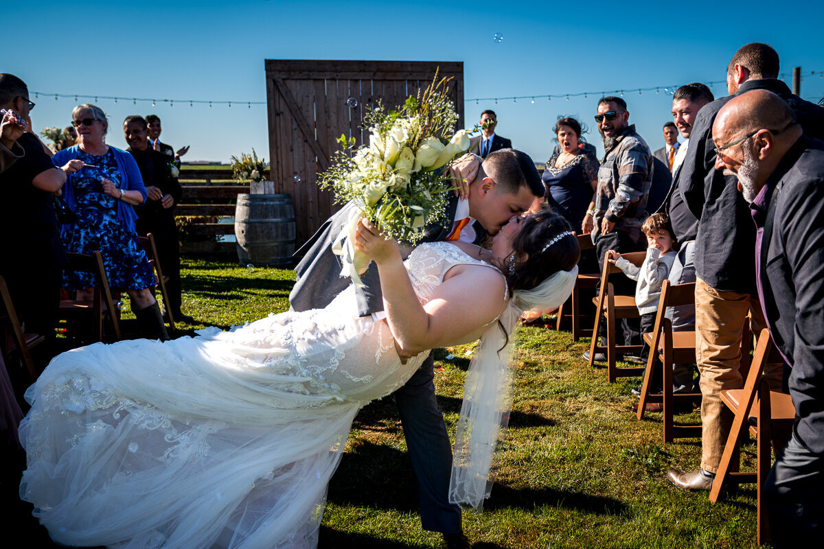 A captivating moment as the groom sweeps his bride into a dip and seals it with a kiss just after their ceremony at The Barn by Fernbridge. This stunning shot captures the joy and romance of their special day, framed by the rustic charm of this Ferndale wedding venue. Perfect for showcasing love and elegance in Northern California weddings.