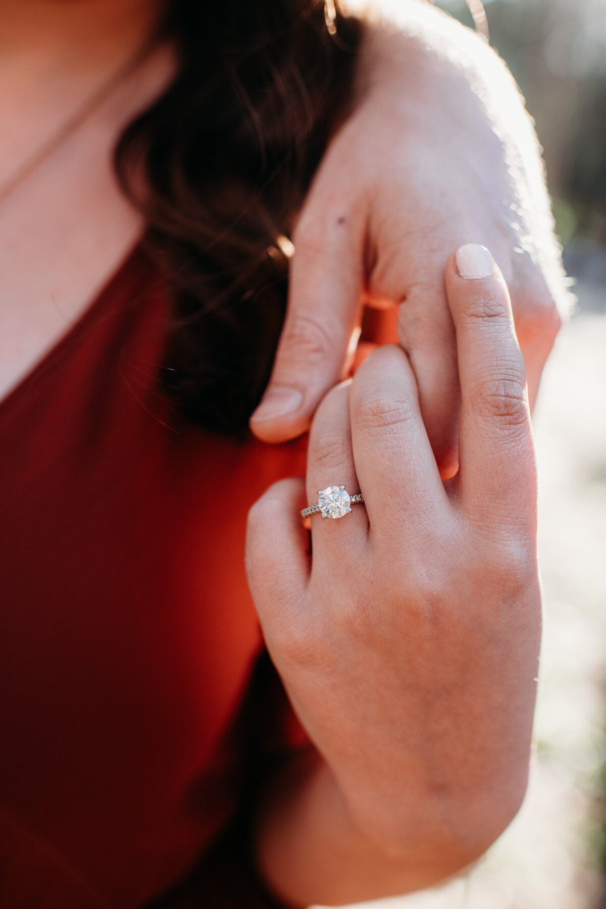 Woman holding man's hand showing off her engagement ring