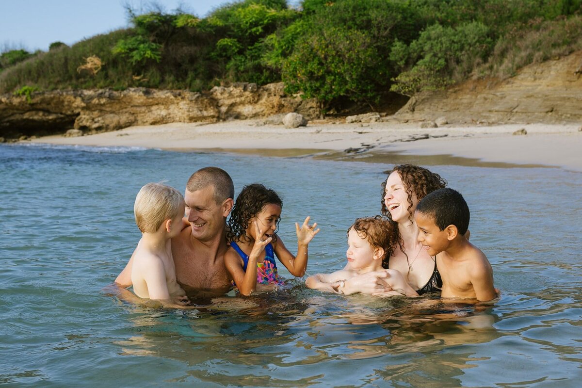 A family of six play in the water of the ocean.