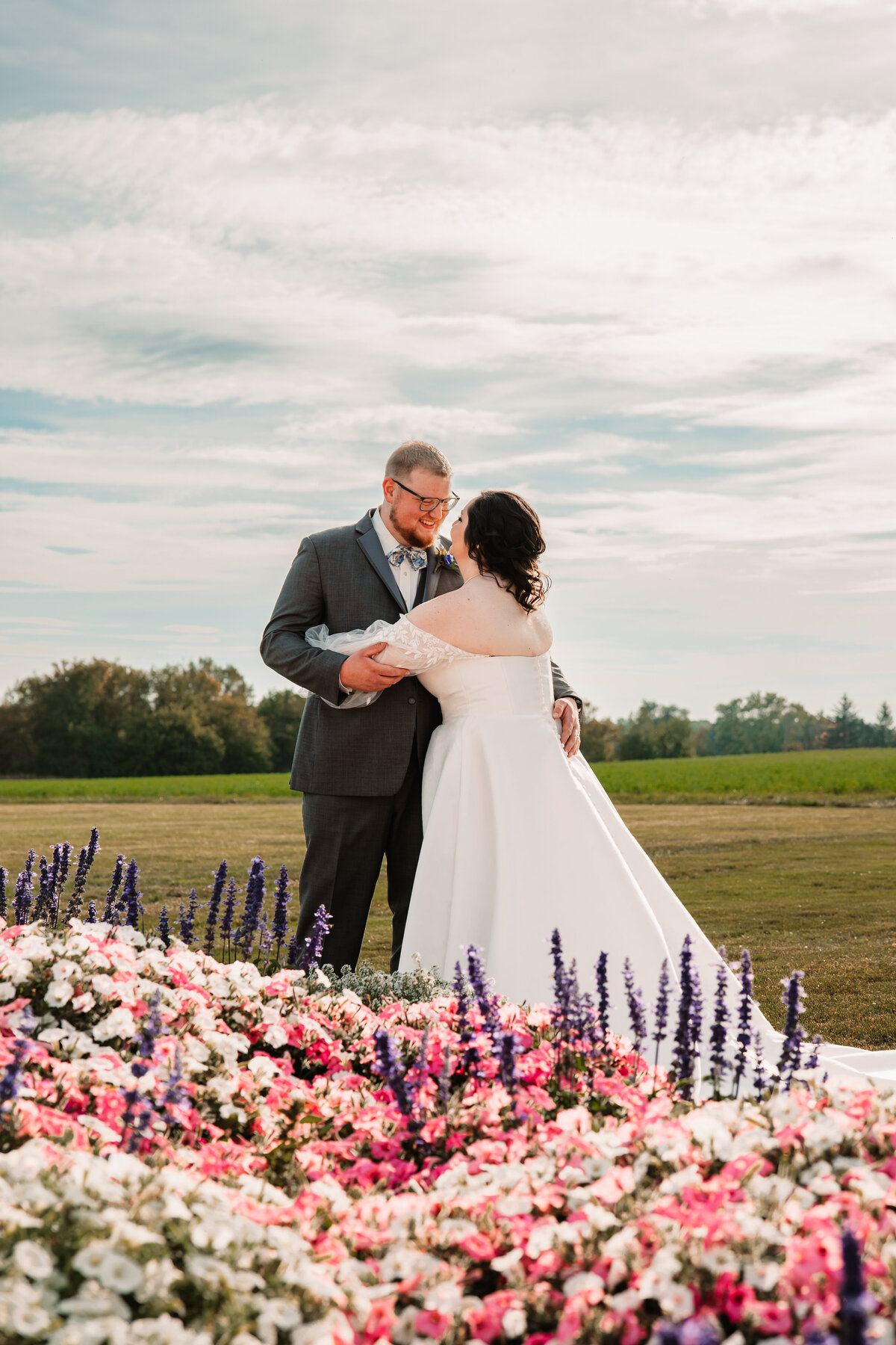 Newlyweds dance while exploring a garden of vibrant flowers at sunset