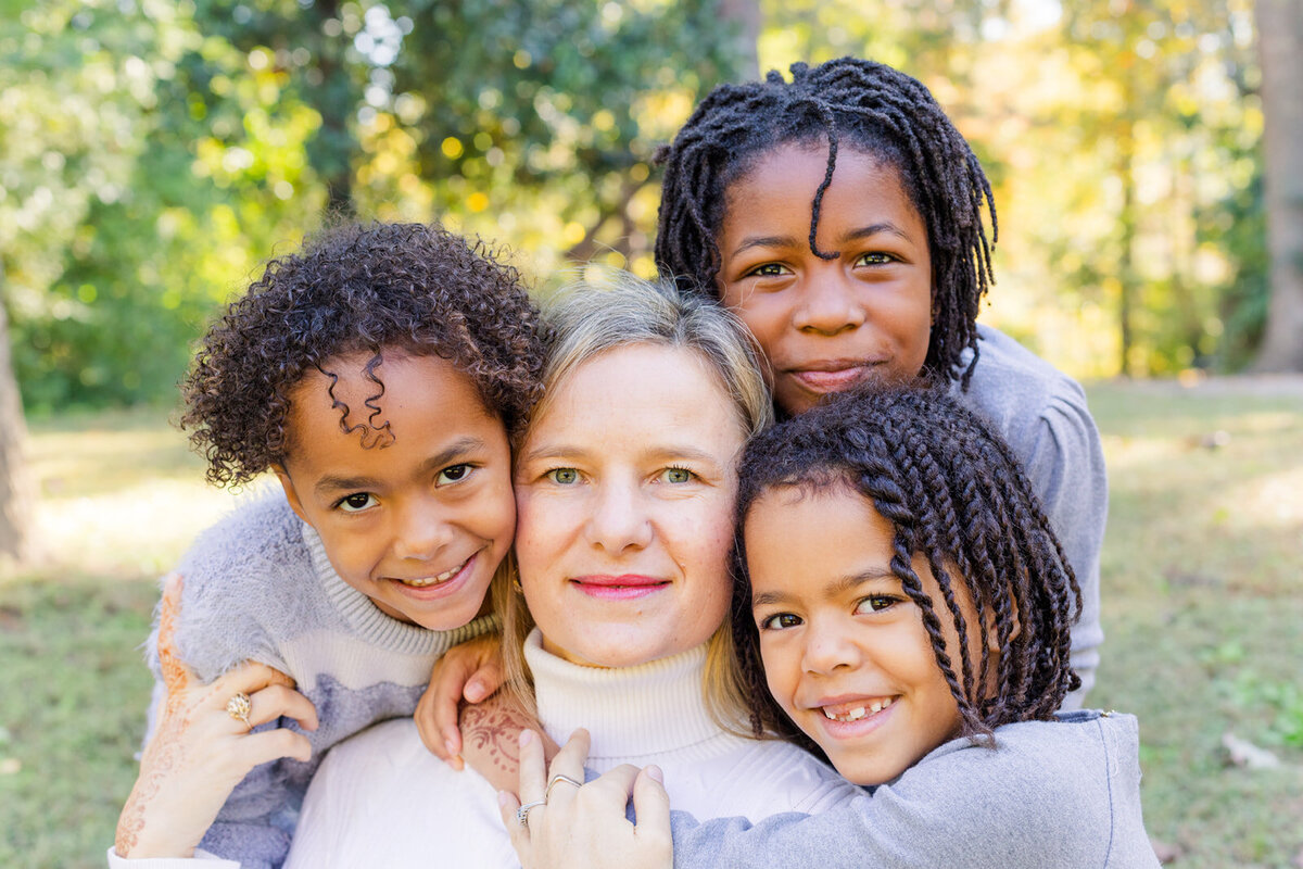close up mum with brown color daughters wearing white and grey hugging in a park in Atlanta GA