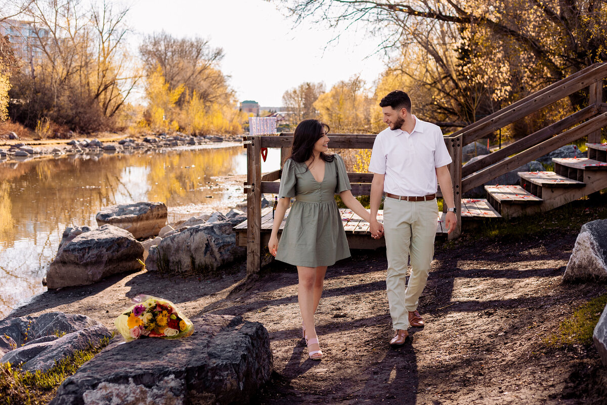 newly engaged couple holding hands and staring at each other while walking towards the camera