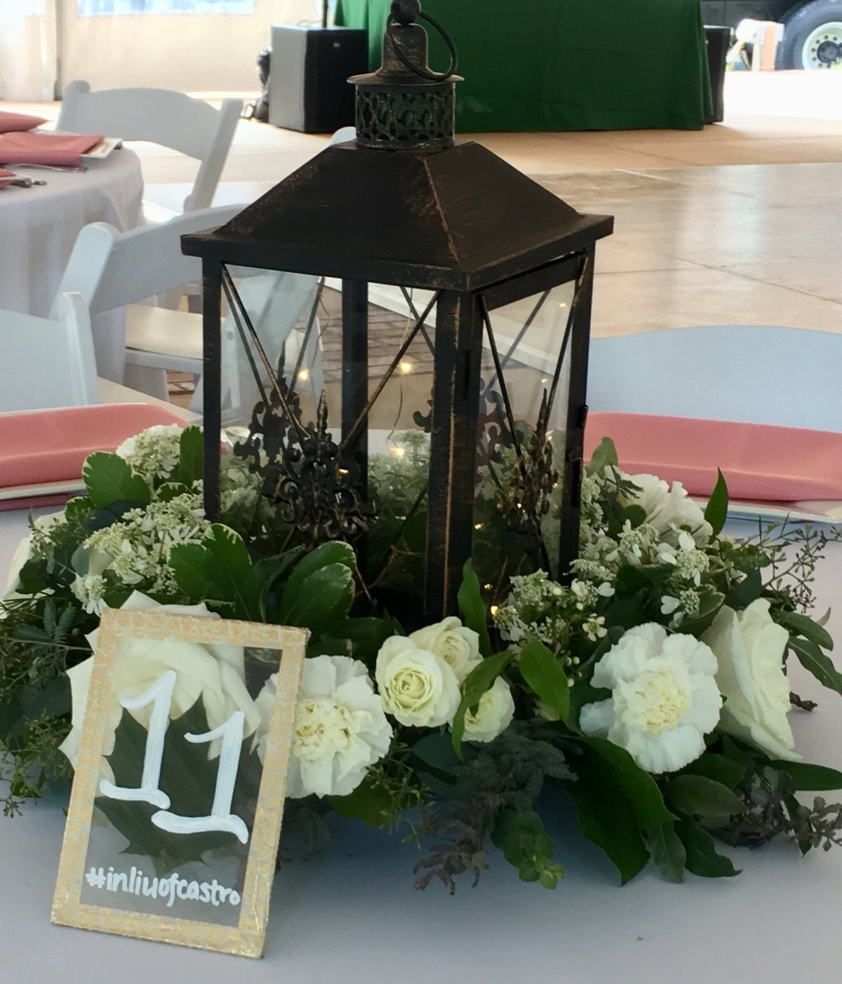 White floral centerpiece with  a  candle holder in the center.