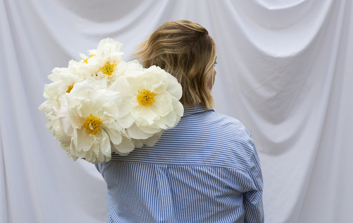 Graphic, web and branding designer Bess Brownlee holds peonies outside in Missoula, Montana.