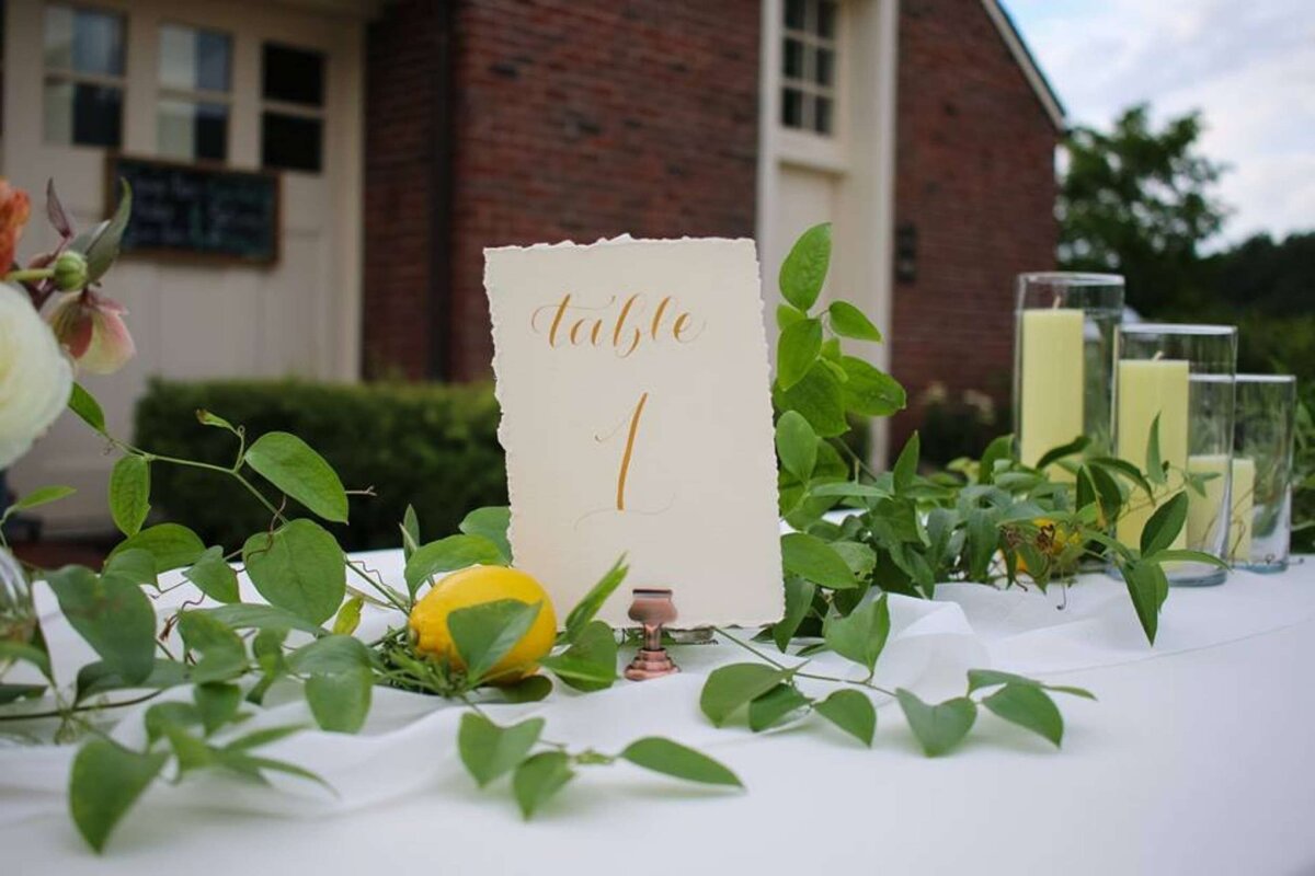 Greenery and lemon accents down the table with ivory and gold table numbers at a luxury Italian inspired Chicago North Shore wedding.
