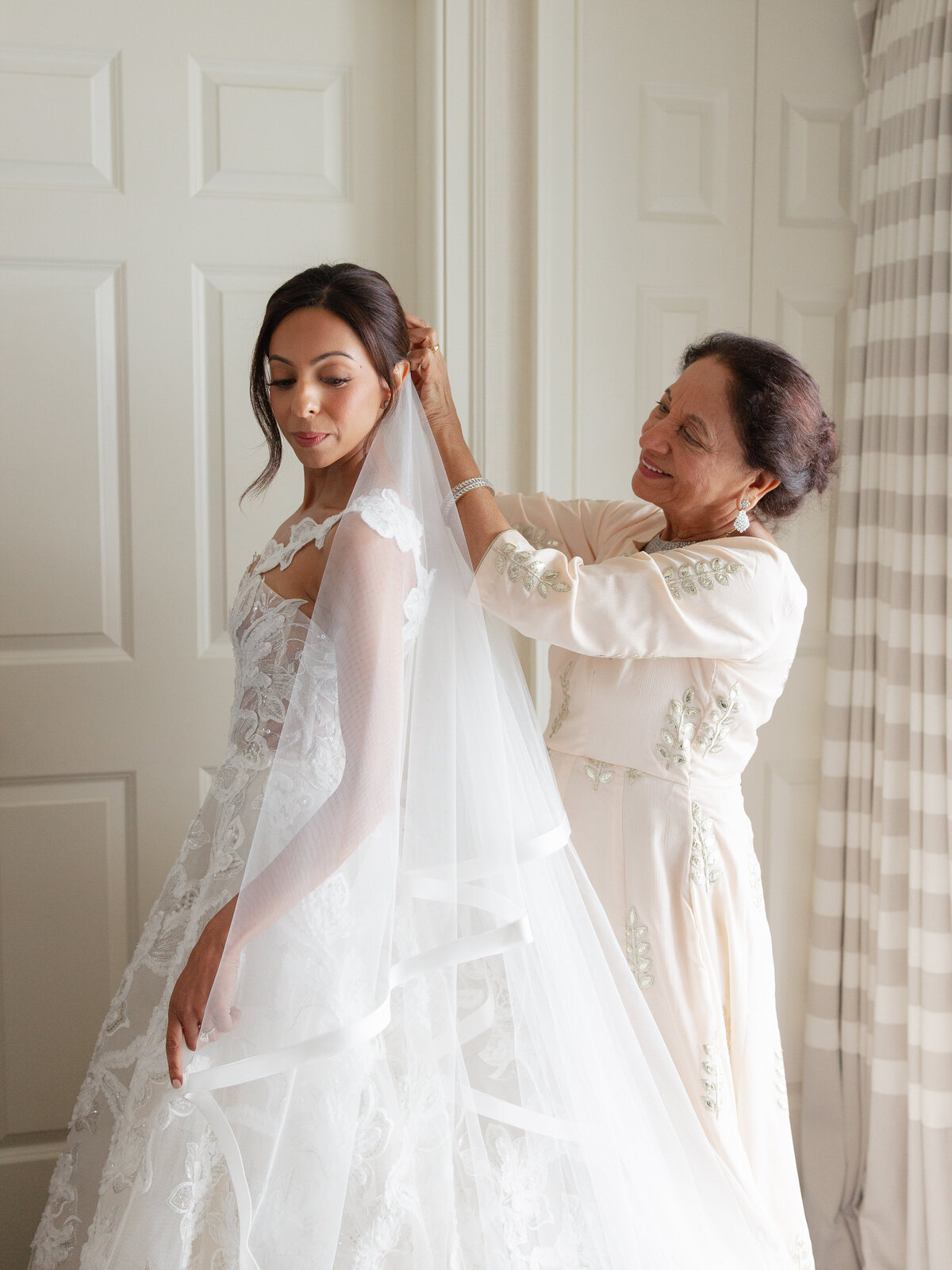 Mother of bride putting bride's veil on