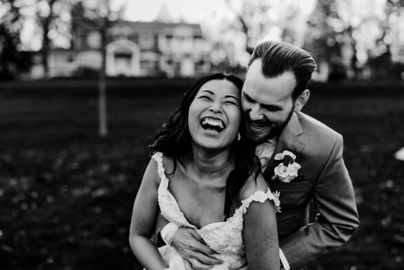 black and white photo of a bridge being hugged by her groom and laughing