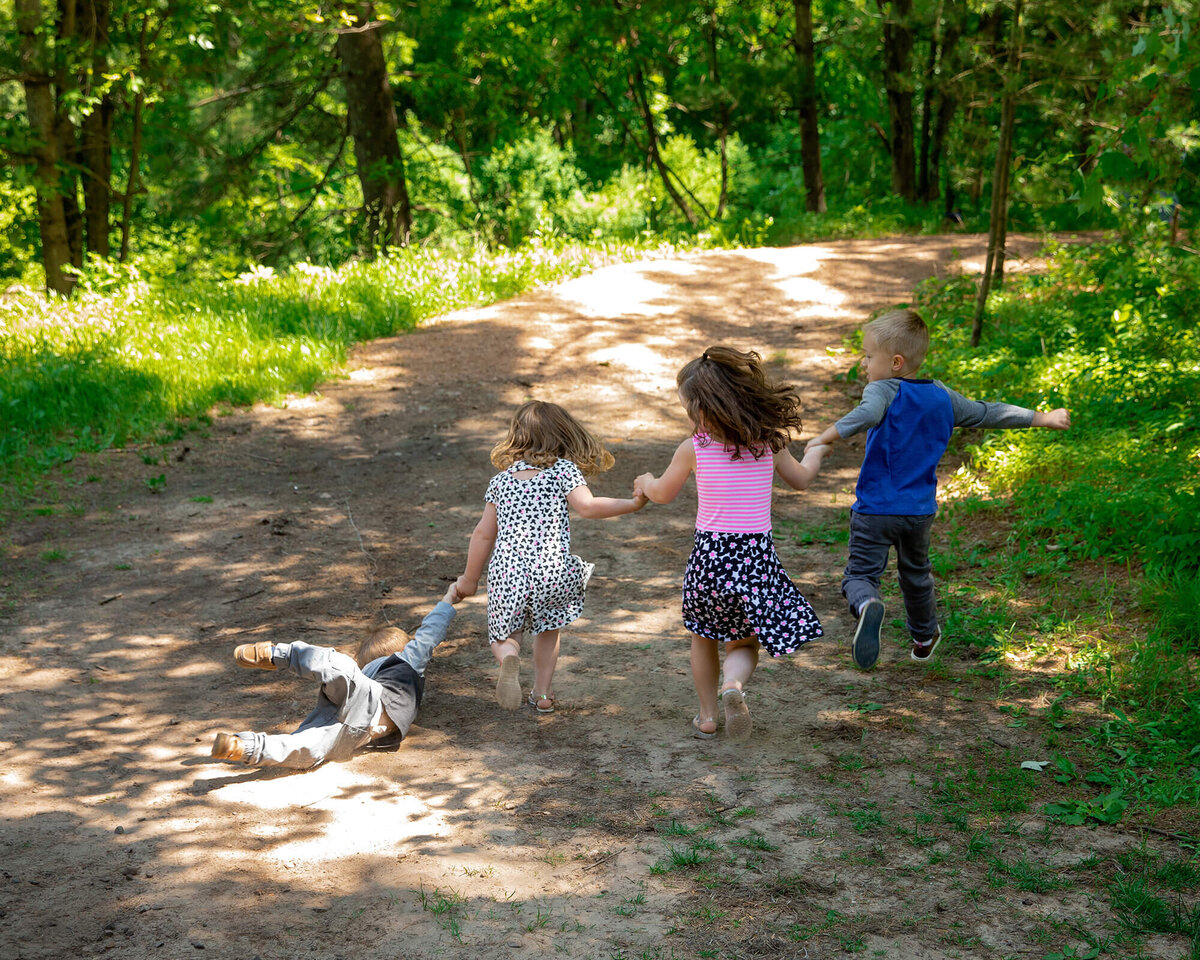 4 cousins running away into the woods with the littlest of the cousins falling and being pulled.