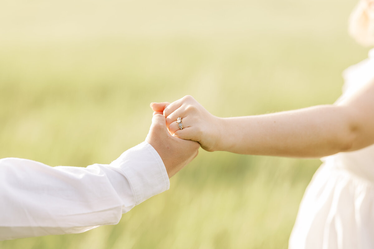 close up of an engaged woman's hand holding her fiance's and showing off the ring