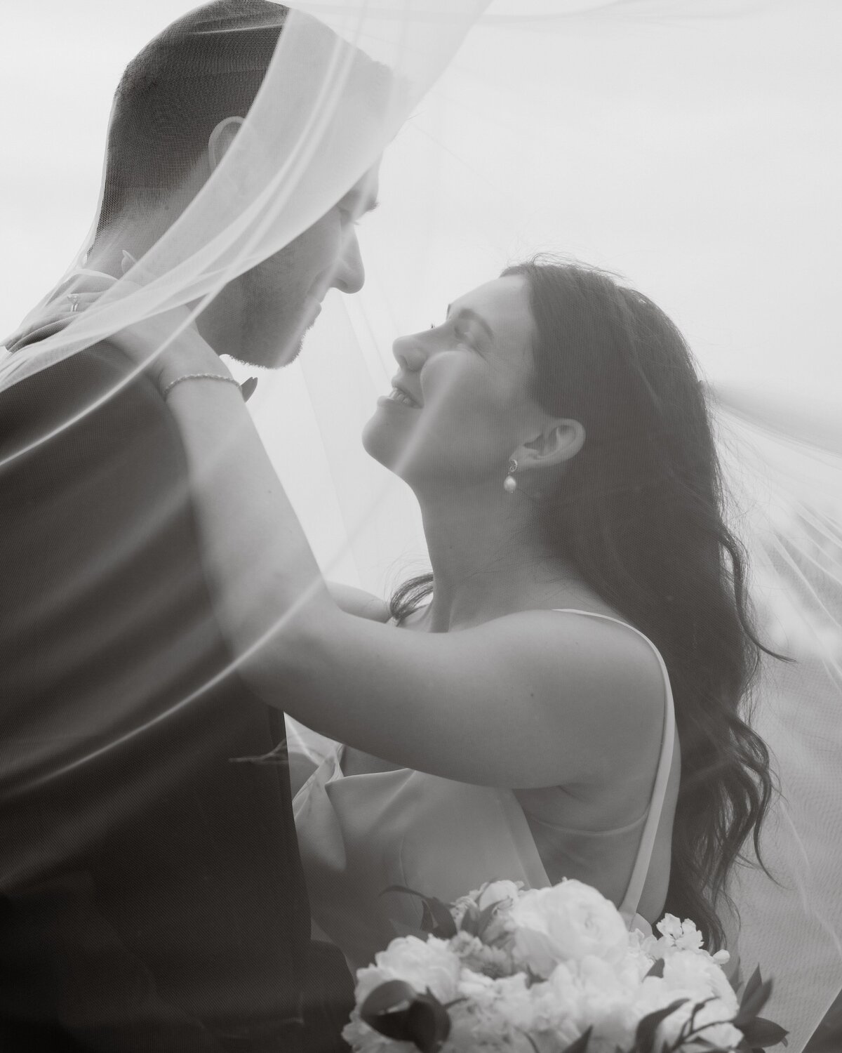newlyweds looking deeply into each others eyes covered by her veil