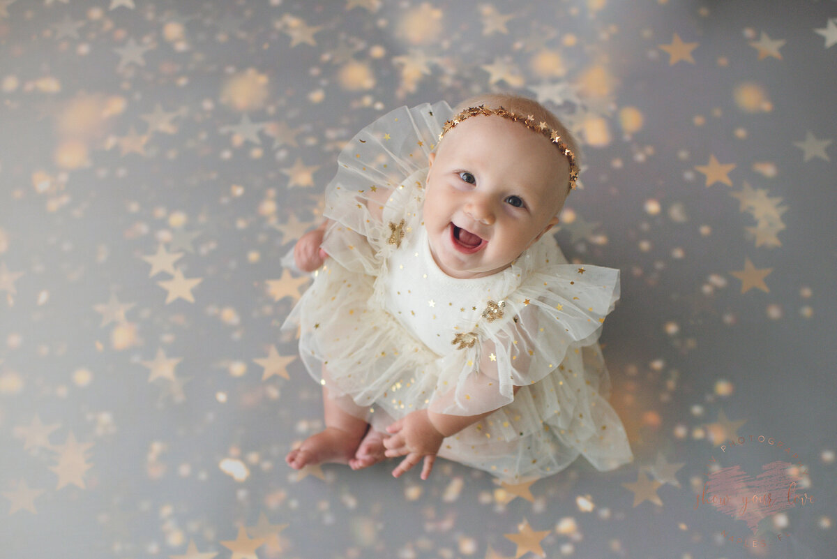 one year old girl surrounded by star confetti