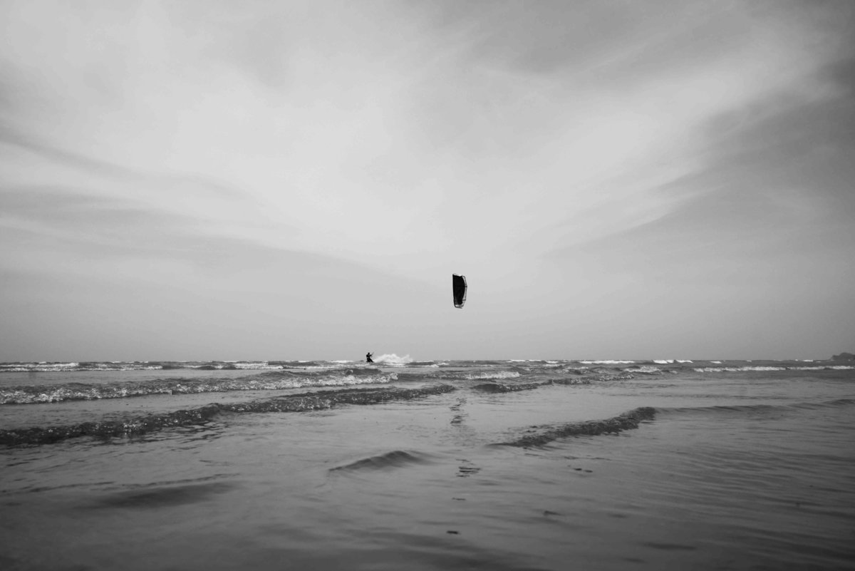 B+W artistic capture of kite surfing kite on the beach nd in the distance. Photo by Ross Photography, Trinidad, W.I..