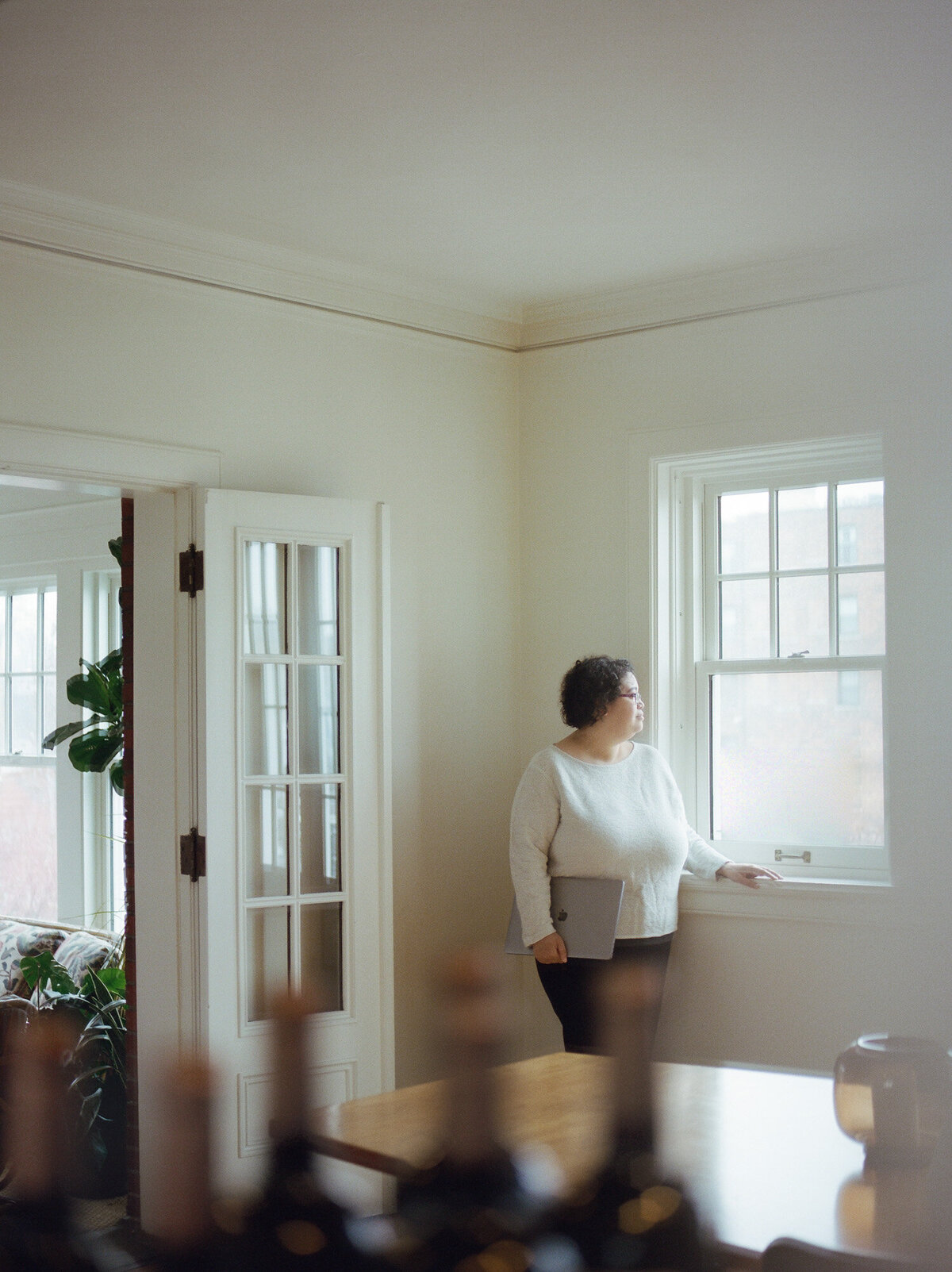 woman in white sweater looks out window, ALEO Detroit, web designer branding photo